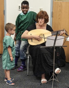 Holly Hart/The News-Gazette Kelli McQueen (right) of Urbana plays the Lute as Brody Wilson 6 years old of Rantoul (left) and Marcus Smith 11 years-old of Chicago help her sing a song. Medieval Afternoon at the Rantoul Public Library featuring food, dances, costumes, demonstrations, crafts and faux sword fights. Saturday, July 18, 2015.