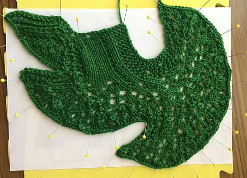 a photograph of a knit pattern in a very strange shape, using green yarn