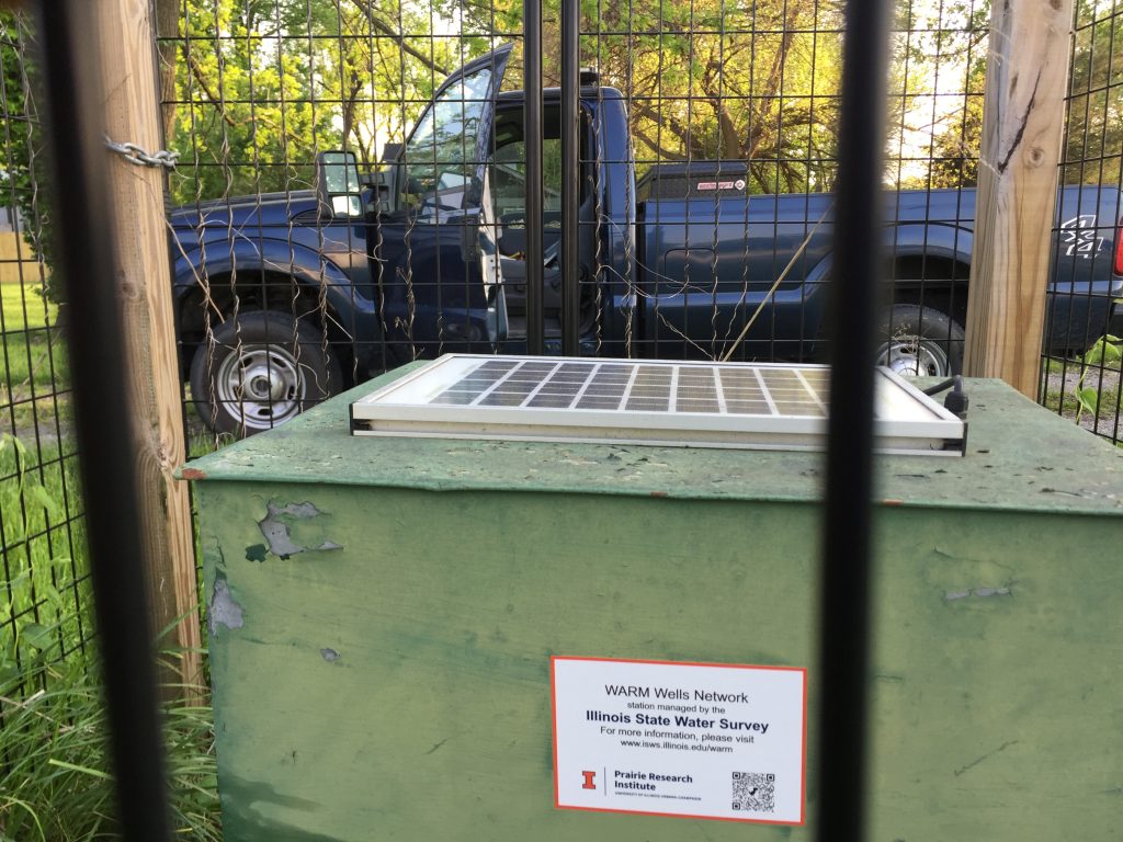 A telemetry box and solar panel, with our research truck in the background. This well monitoring system is marked as a WARM (Water and Atmospheric Resources Monitoring) network well.