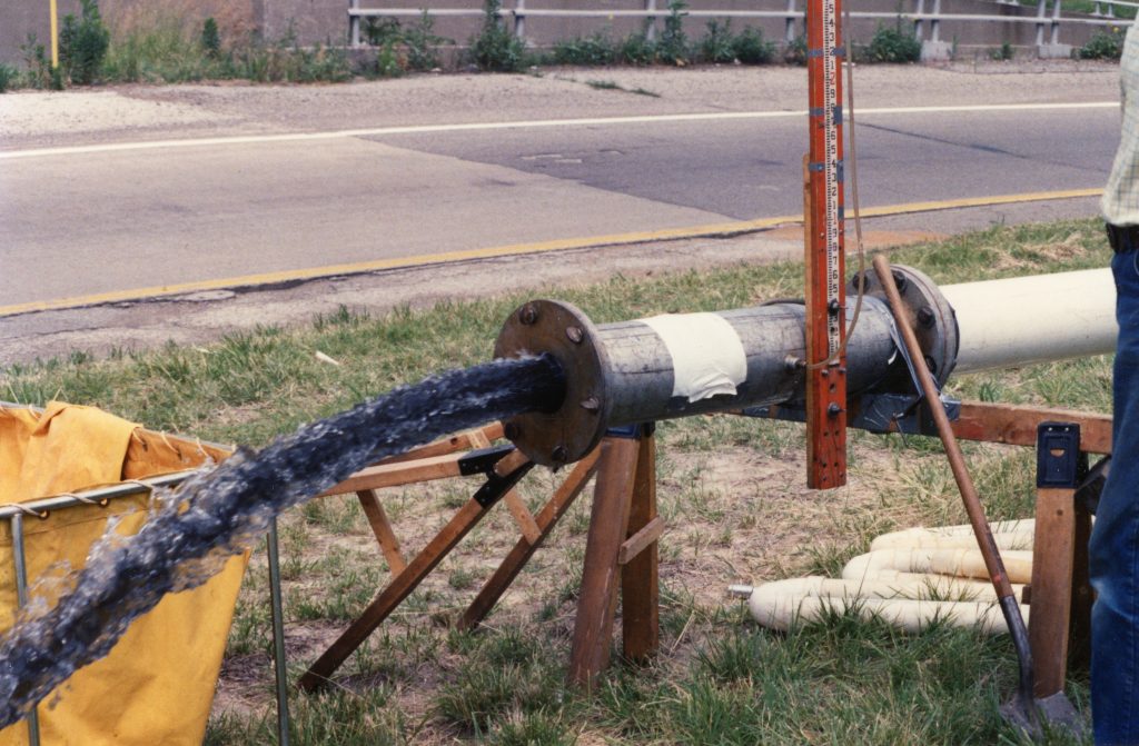 Dark gray/black water being ejected from a pump during well treatments. The water color is likely due to high iron content.