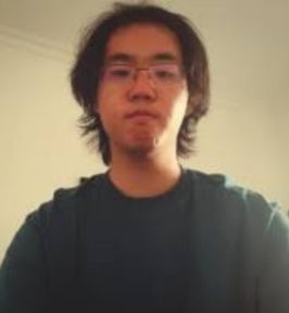 Portrait of Jixin Li looking at the camera. He has medium-length dark hair and is wearing glasses, a dark T-shirt, and a hoodie. The background is plain and light-colored, giving the image a simple, informal headshot appearance