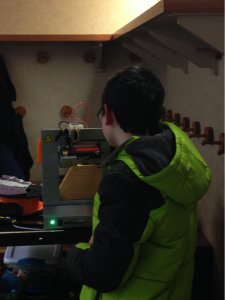 Teen waits for his 3D project to finish printing.