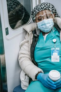 Exhausted nurse wearing mask rests on metro
