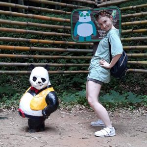 woman standing in the same pose as a panda statue