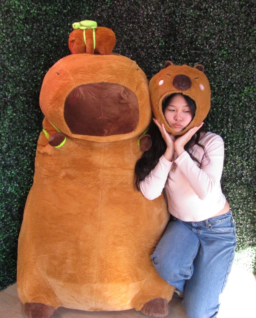 a photo of LAS 102 Intern, Jess Chen dressed up as a capybara alongside a capybara plushie