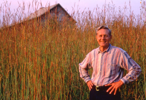 man standing in front of tall prairie plants