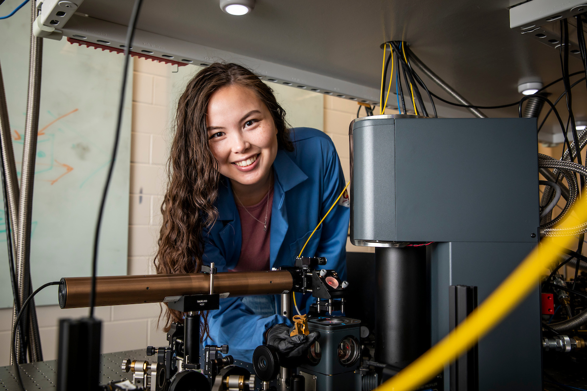 An Asian student wearing a blue blouse smiles over her research device