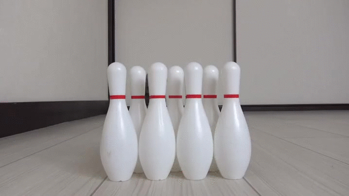 A gif of a cat trying to bowl but knocking down the pins with its body