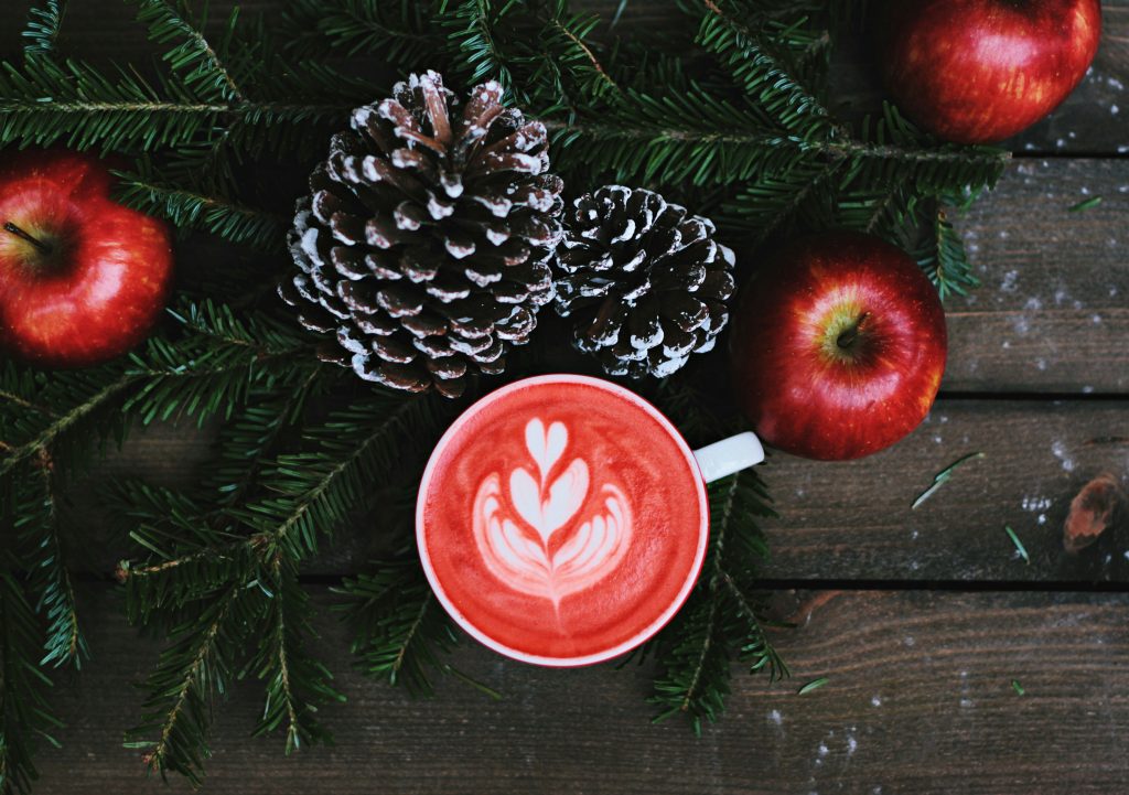 cozy winter scene with evergreens and a red latte, signifying the end of the semester and the start of a break