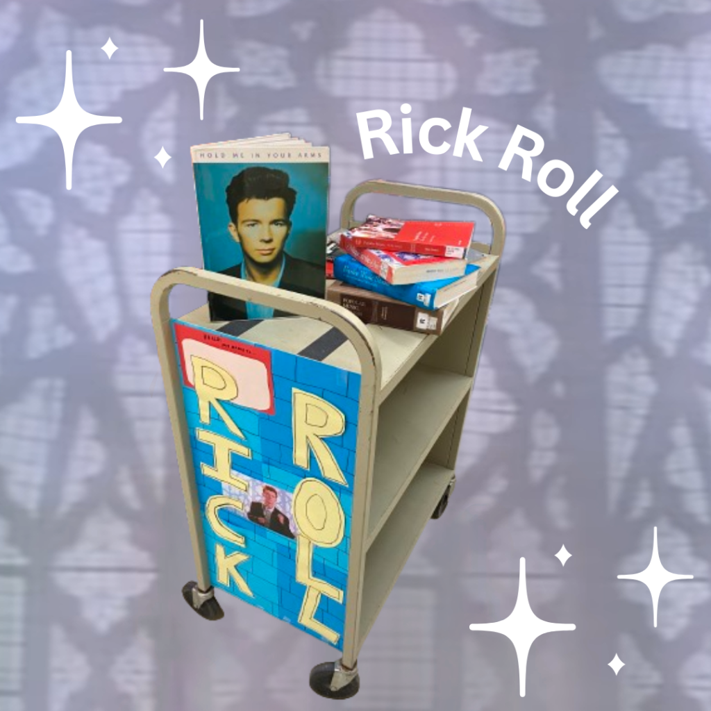 A library cart decorated with the words "Rick Roll" and materials dedicated to Rick Astley appears in front of a background similar to that of the musician's video for "Never Gonna Give You Up"