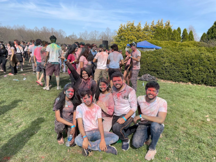 A group of students pose, covered in colored powder.