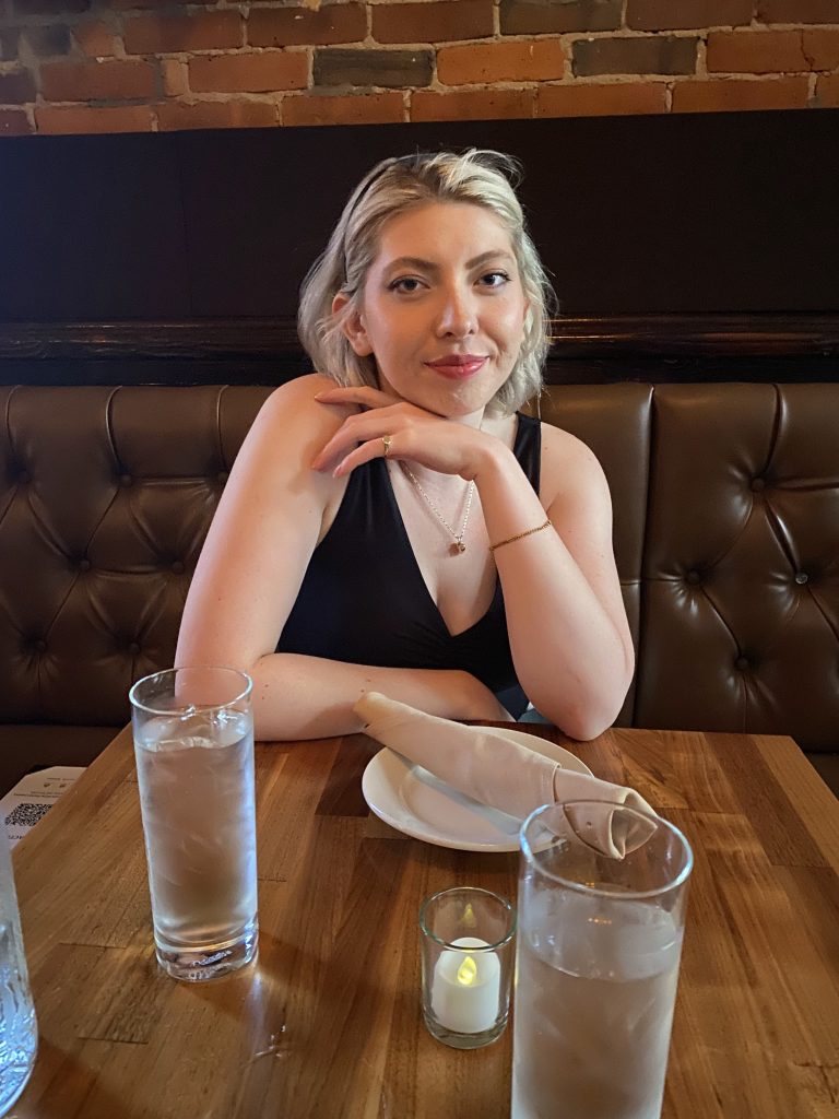 Rachel, a woman with short blonde hair, sits at a restaurant table.