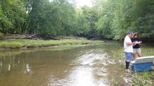 2 people standing at edge of river.