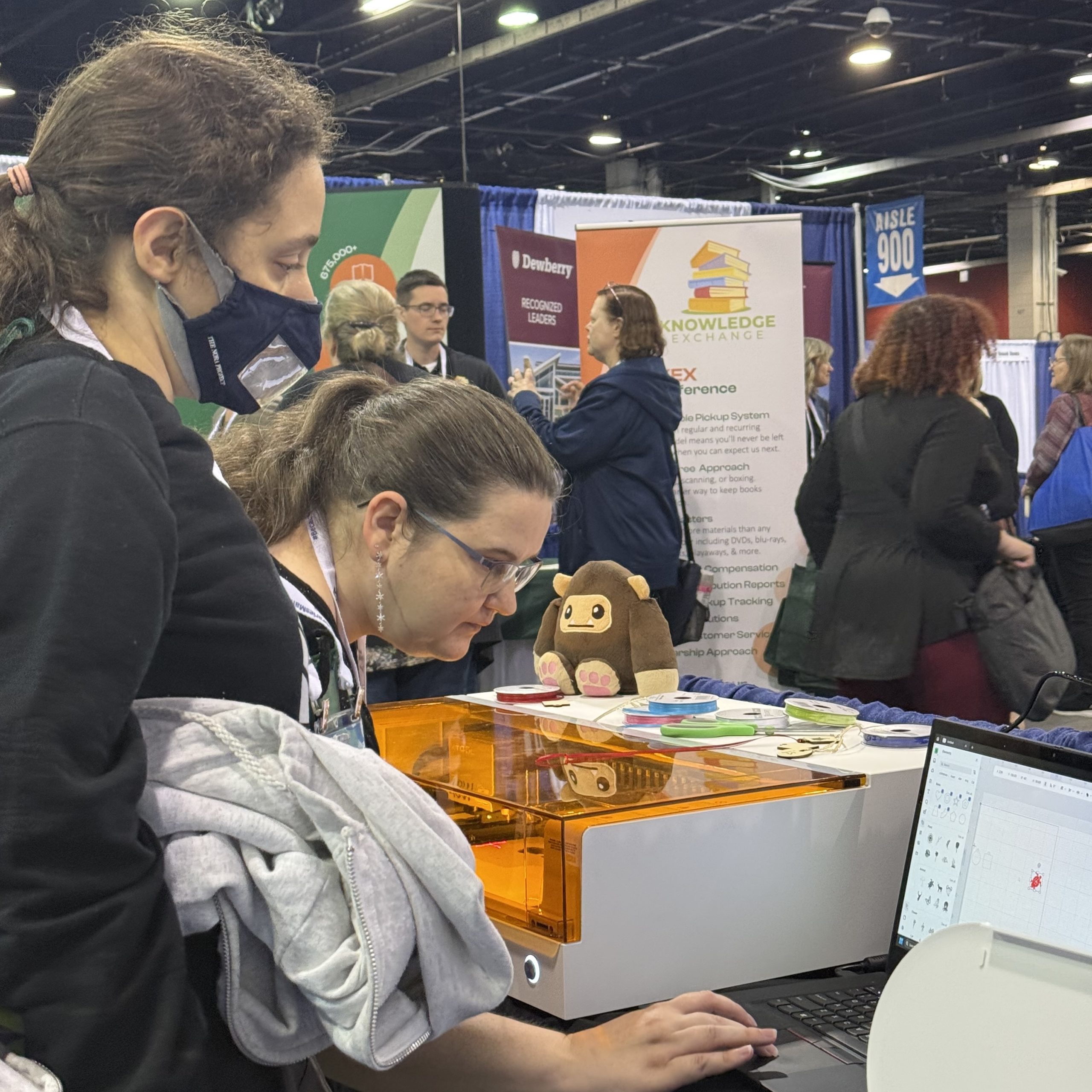 A staff member shows an attendee the computer program running a laser sitting next to them