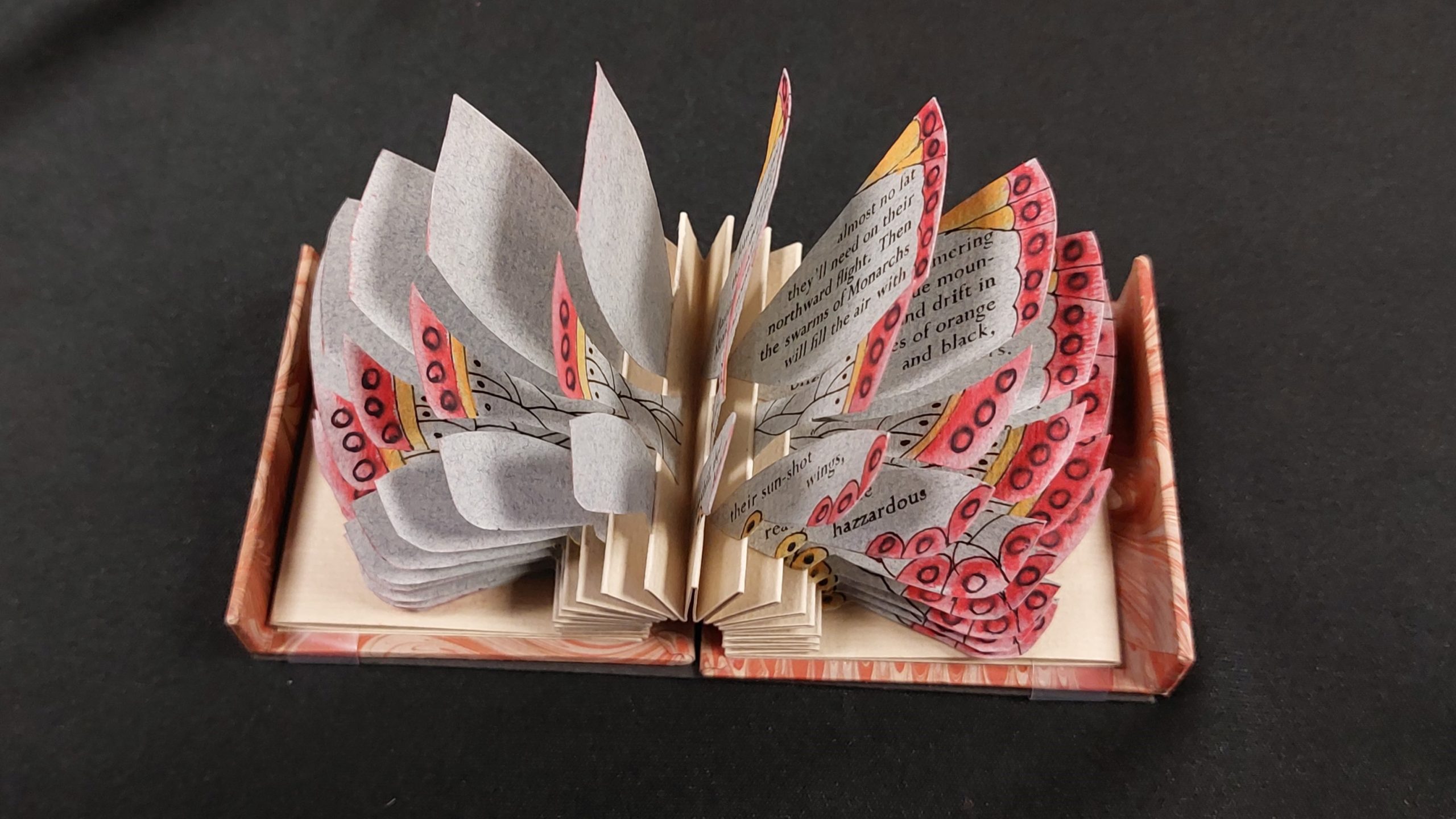 Photo of a whimsical artist's book with leaves splayed out invoking the appearance of a butterfly.