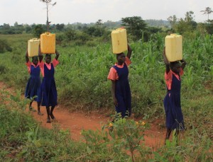 Four African school children in uniforms carrying water