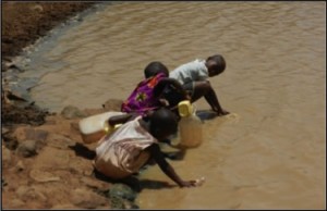 Three african children collecting water from a muddy pool.