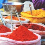 Red, orange, and gold spices in bags with spoons