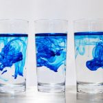 Three glasses of water with blue dye diffusing through them in different swirling patterns